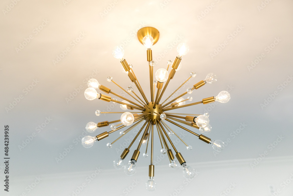 Wall mural Retro starburst warm gold lighting fixture against a white wall