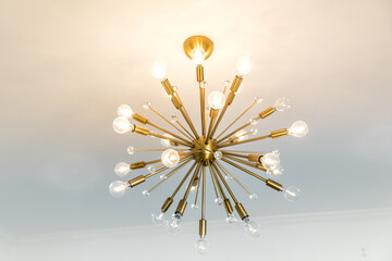 Retro starburst warm gold lighting fixture against a white wall - Powered by Adobe