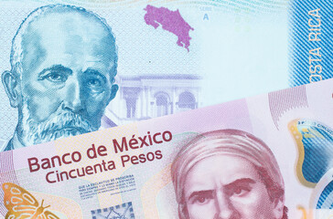 A macro image of a pink, plastic fifty peso bank note from Mexico paired up with a colorful two thousand colones bank note from Costa Rica.  Shot close up in macro.