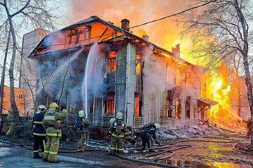 Firefighters extinguish a fire in a two-story wooden house