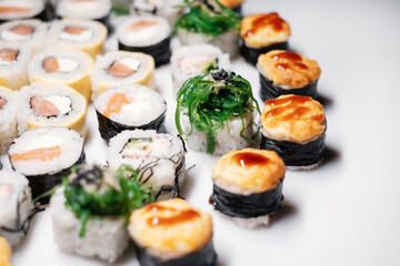 Japanese food restaurant.  Sushi roll set maki california  at white background, above view decorated with leaves flat lay side view.
