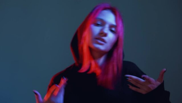 Neon light dance. Hip hop style. Street fashion. Rap performance. Cool stylish confident young woman in urban clothes dancing in vibrant night club neon light.