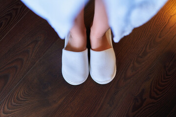 Female feet in white soft disposable hotel slippers - obrazy, fototapety, plakaty