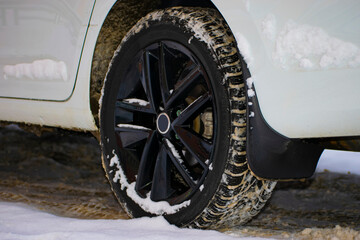 A car standing in the snow. Part of the Car. Rear wheel with mudflap. Selective focus. Close-up
