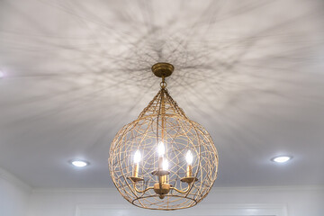 Modern gold cage next style chandelier in a white room