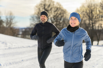 mature couple in the winter running together in nature
