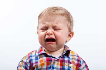 Ni&ntilde;o llorando. Ni&ntilde;o con camisa con cuadros sobre fondo blanco llorando.