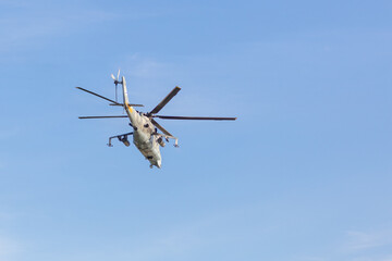 A Russian military helicopter is high in the peaceful blue sky. Military forces, defense and defense of the country.