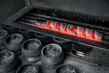 Hot coal for hookah. Heated coal for a hookah on a gray stove background.