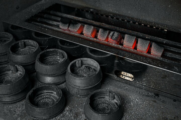 Obraz na płótnie Canvas Hot coal for hookah. Heated coal for a hookah on a gray stove background.