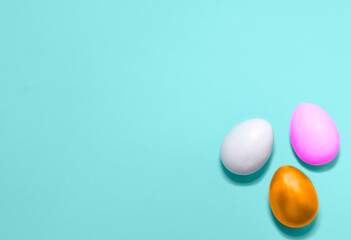 Eggs colored with violet, pink and gold colors in a corner on a blue background. Flat lay. Easter holiday concept. Copy space for text, mock up. Banner.