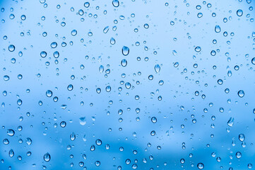 Water drops on glass natural bright blue background. Humidity background