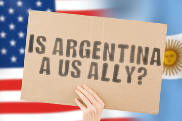 The question " Is Argentina a US ally? " on a banner in men's hand with blurred American and Argentinian flag on the background. Union. Togetherness. Conclusion. Confrontation. Report. Global. Liberty