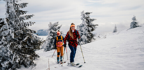 Mountaineer backcountry ski walking ski woman alpinist in the mountains. Ski touring in alpine landscape with snowy trees. Adventure winter sport. Freeride skiing