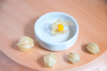 Phisalis inside a white dish with some fruit inside the peel around
