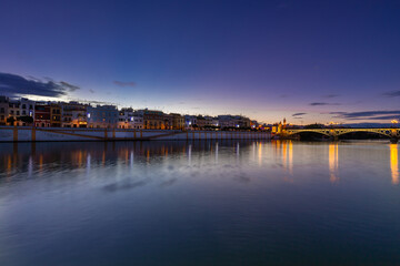 Sunset over the river Guadalquivir in downtown Seville with amazing colors in the sky and a view on the riverside of  the Triana neighbourhood.