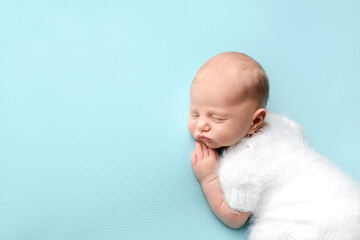 Sleeping newborn baby on a blue background. Photoshoot for the newborn. A few days from birth.