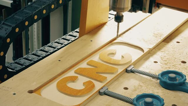 Woodworking CNC machine bit cuts out wooden letters, close-up time lapse