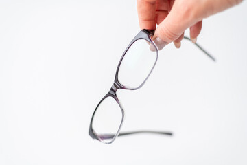 Fototapeta na wymiar Glasses for vision correction in female hand on white