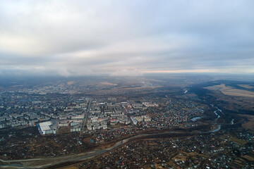 Aerial view of rural homes and distant high rise apartment buildings in city residential area during cloudy weather