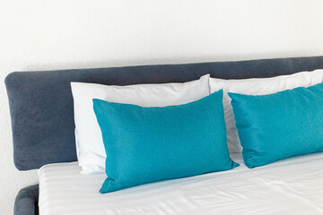 Two beds in a hotel room. white and blue pillows on a white sheet sunbeams