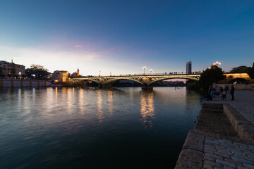 Fototapeta premium Sunset over the river Guadalquivir in downtown Seville with amazing colors in the sky and a view on the riverside of the Triana neighbourhood.