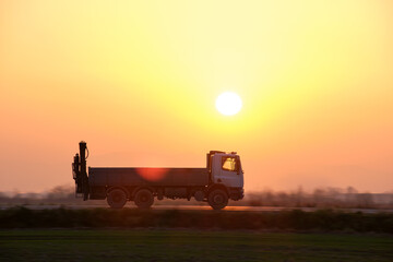 Fototapeta premium Cargo dump truck driving on highway hauling goods in evening. Delivery transportation and logistics concept