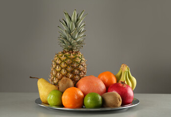 Plate with different ripe fruits on grey table