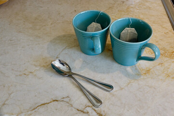 pair of coffee mugs and teaspoons sitting on the kitchen counter