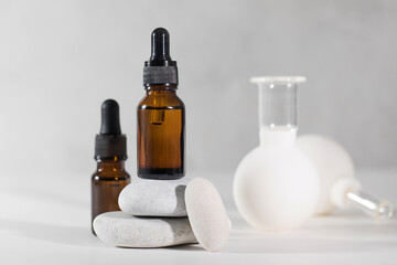 Brown droppers with cosmetics on a pedestal of stones and vacuum cupping massagers in the background.