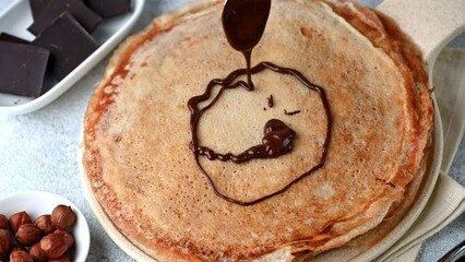 Pancakes with chocolate and nuts. Pouring chocolate on pancakes. Pouring chocolate on crepes. Maslenitsa blini. Shrovetide holiday. Shrove tuesday. Pancake day.