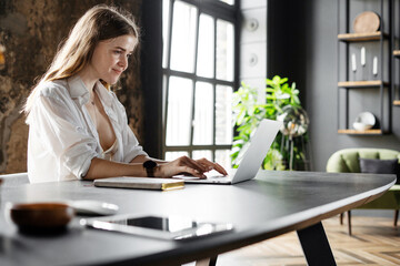 A female financier works in a hotel workplace uses a laptop, communicating with a client.