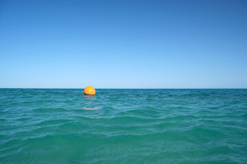 Orange buoy floating on sea surface waves. Human life safety concept