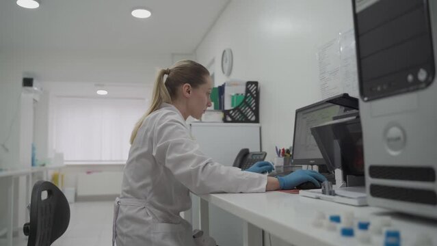 Scientist woman works at her workplace in laboratory, uses personal computer. Development, analyzes and genetics. Pharmaceutical Research Center. Microbiologist checks data on computer in the lab.