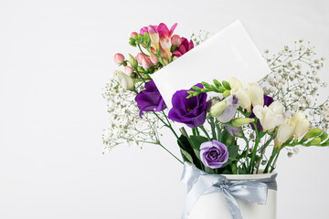 Beautiful Spring, summer flowers in vintage ceramic vase with ribbon, and Blank greeting card on white background.  Mock up, empty copy space.
