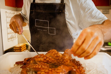 Cook (Chef) holds a whole fresh octopus in his hands. Cooking octopus. An unrecognizable person. Seafood dishes. Protein food. Free space