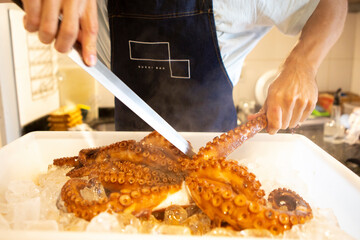 Cook (Chef) holds a whole fresh octopus in his hands. Cooking octopus. An unrecognizable person. Seafood dishes. Protein food. Free space
