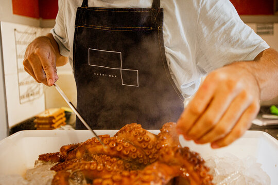 Cook (Chef) holds a whole fresh octopus in his hands. Cooking octopus. An unrecognizable person. Seafood dishes. Protein food. Free space