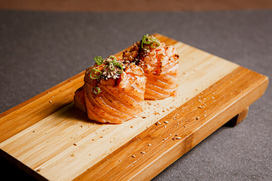 Salmon sushi freshly prepared. Japanese food, sushi roll of salmon in a wooden background. Fish and crustaceans slices. Front view with Copy Space.