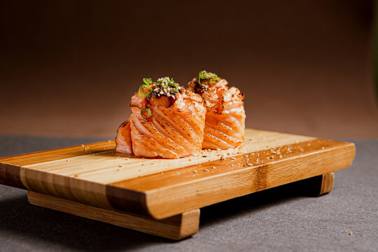 Salmon sushi freshly prepared. Japanese food, sushi roll of salmon in a wooden background. Fish and crustaceans slices. Front view with Copy Space.