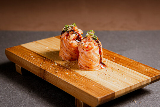 Salmon sushi freshly prepared. Japanese food, sushi roll of salmon in a wooden background. Fish and crustaceans slices. Front view with Copy Space.
