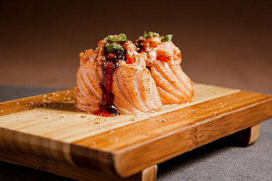 Salmon sushi freshly prepared. Japanese food, sushi roll of salmon in a wooden background. Fish and crustaceans slices. Front view with Copy Space.