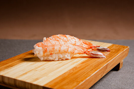 Sushi freshly prepared. Japanese food, sushi roll of shrimp in a wooden background. Fish and crustaceans slices. Front view with Copy Space.