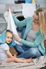 mother and baby loading clothes into washing machine