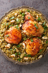 Freekeh with chicken is a delicious meal made with the grain and served with toasted nuts and herbs closeup in the plate on the table. Vertical top view from above