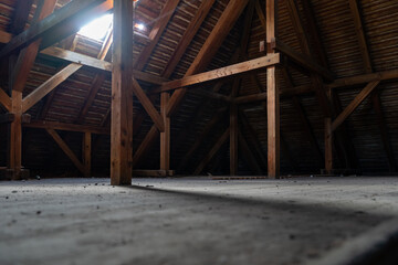 Old dusty attic of a building. Empty space lit by a roof window. Wooden construction of the roof....