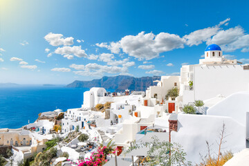 View from a whitewashed terrace of the caldera, sea and village of Oia, Santorini, Greece, with one of the famous blue dome churches in view. - obrazy, fototapety, plakaty