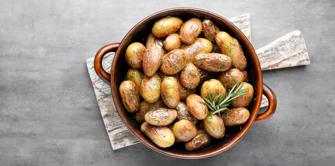 Pan filled with roasted potatoes shot on rustic wooden table.
