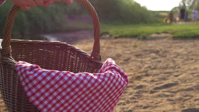 Holding picnic basket with red gingham cloth by the lake shot 