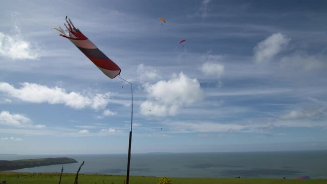 Windsock flying coastal breeze paraglider's soar overhead under a cumulus cloud